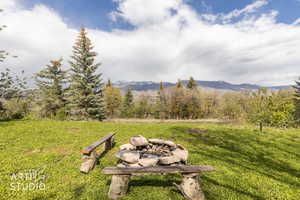View of green lawn featuring an outdoor fire pit and a mountain view