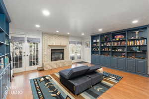 Living area featuring french doors, a fireplace, light wood finished floors, and recessed lighting