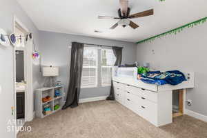 Bedroom featuring light carpet, ceiling fan, and ensuite bathroom