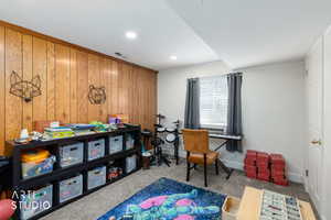 Carpeted home office featuring wooden walls and baseboards