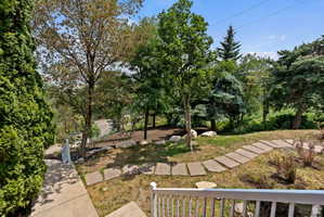 Terraced landscaping featuring a winding stone-paver pathway, mature trees, and natural rock accents