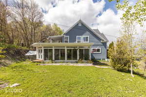 Rear view of house featuring a sunroom and a lawn