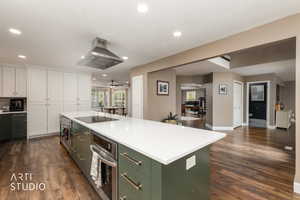 Dual tone kitchen featuring two tone cabinetry, stainless steel oven, dark wood finished floors, island exhaust hood, and open floor plan