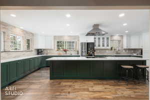 Dual tone kitchen featuring two tone cabinets, stainless steel refrigerator with ice dispenser, recessed lighting, island exhaust hood, and dark wood finished floors