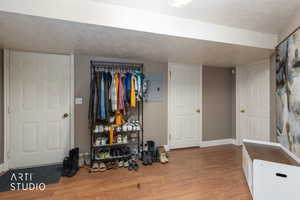 Bedroom with a textured ceiling, light wood-style floors, and electric panel