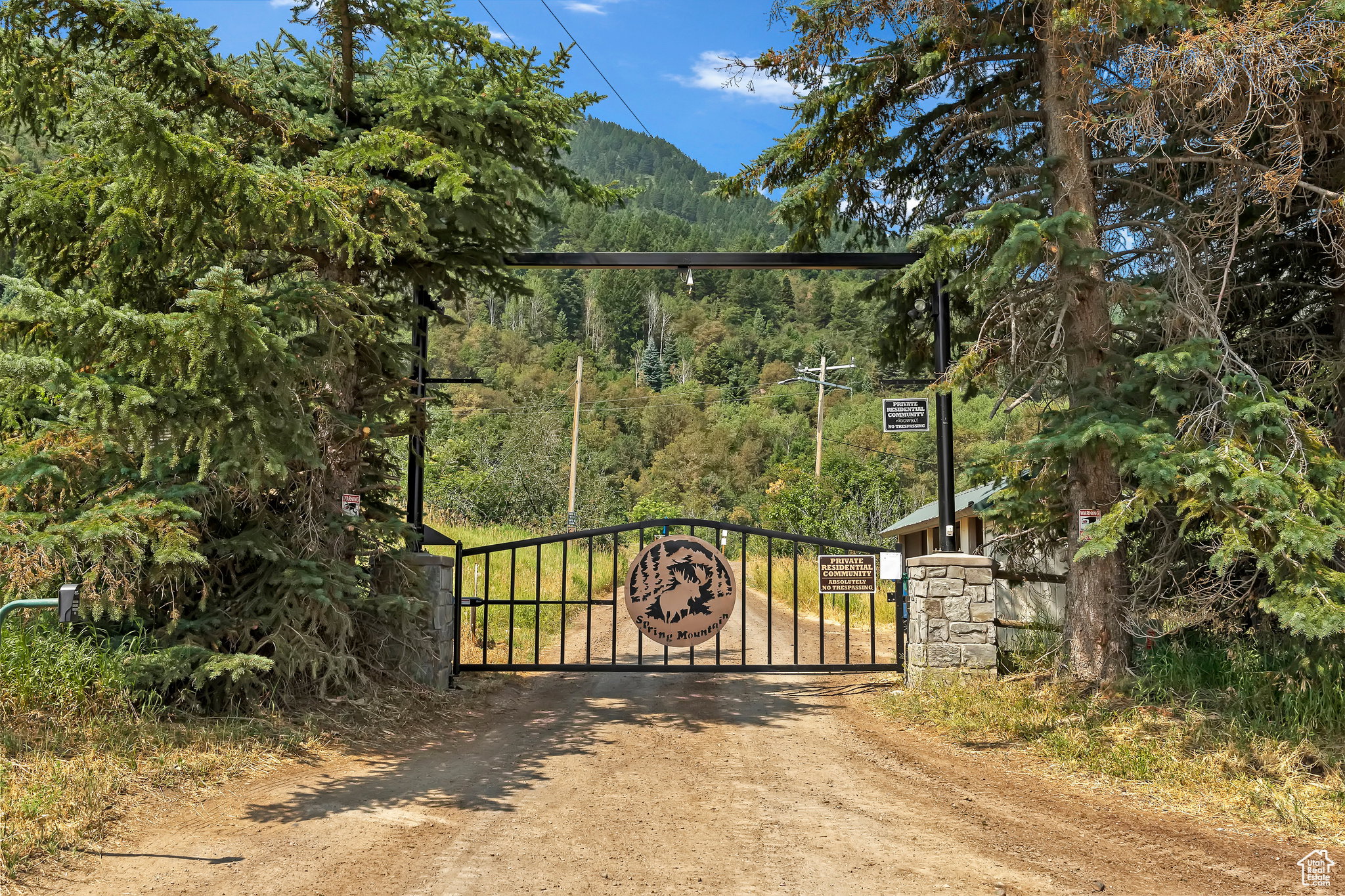 Gated entrance featuring stone pillars and a decorative metal gate with a custom medallion