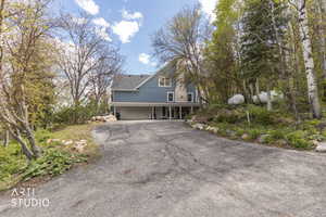 View of front of house with asphalt driveway, covered porch, and a garage