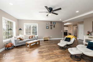 Living area with a ceiling fan, dark wood-style floors, recessed lighting, and a fireplace