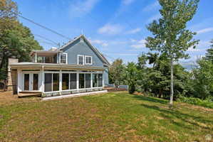 Expansive rear yard with a sloped lawn and mature trees
