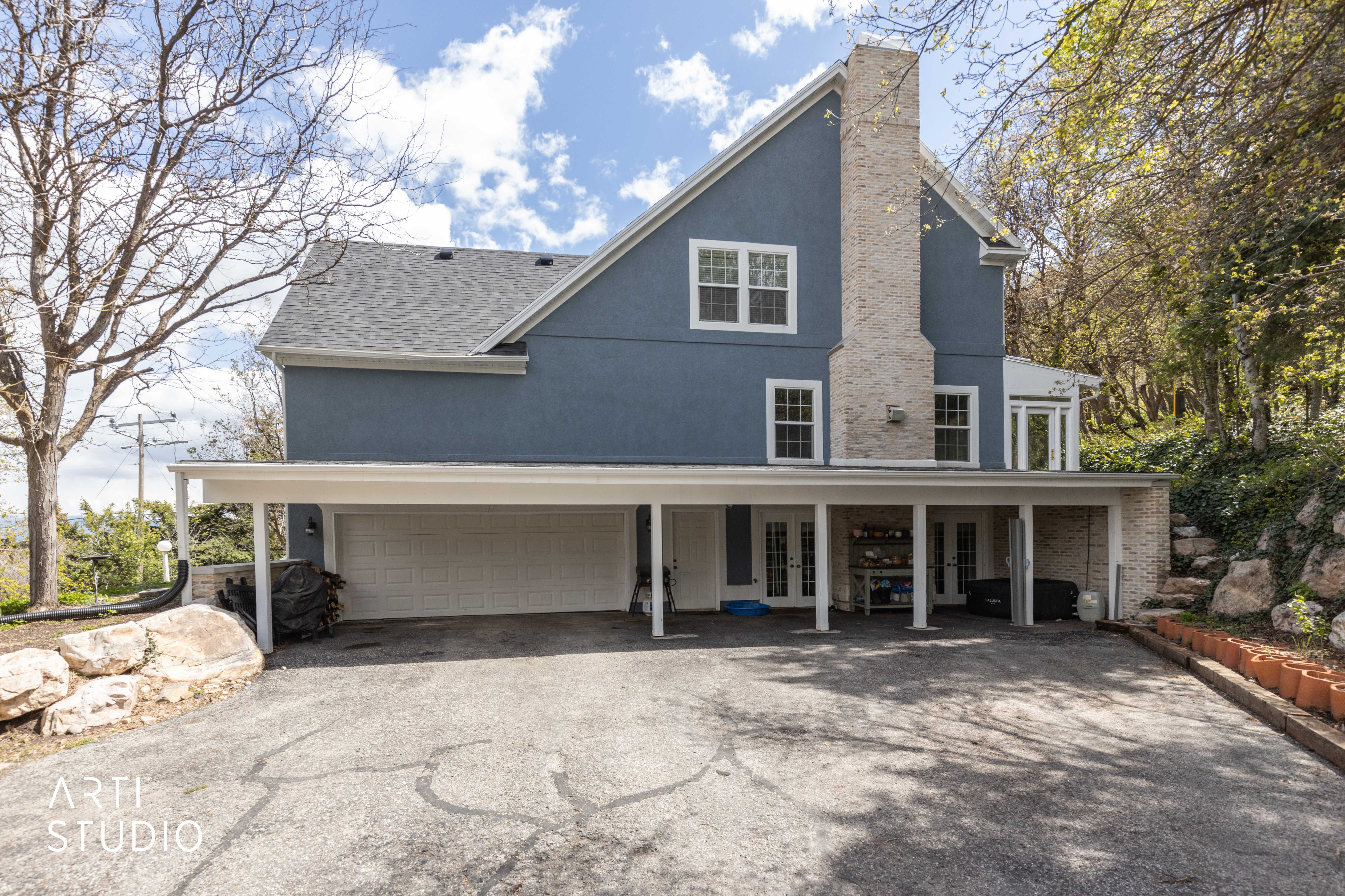 View of front of home featuring asphalt driveway, french doors, stucco siding, a garage, and a chimney