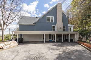 View of front of home featuring asphalt driveway, french doors, stucco siding, a garage, and a chimney