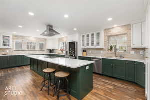 Kitchen featuring glass fronted cabinets, two tone color scheme, a kitchen island, a breakfast bar, and dark wood-type flooring