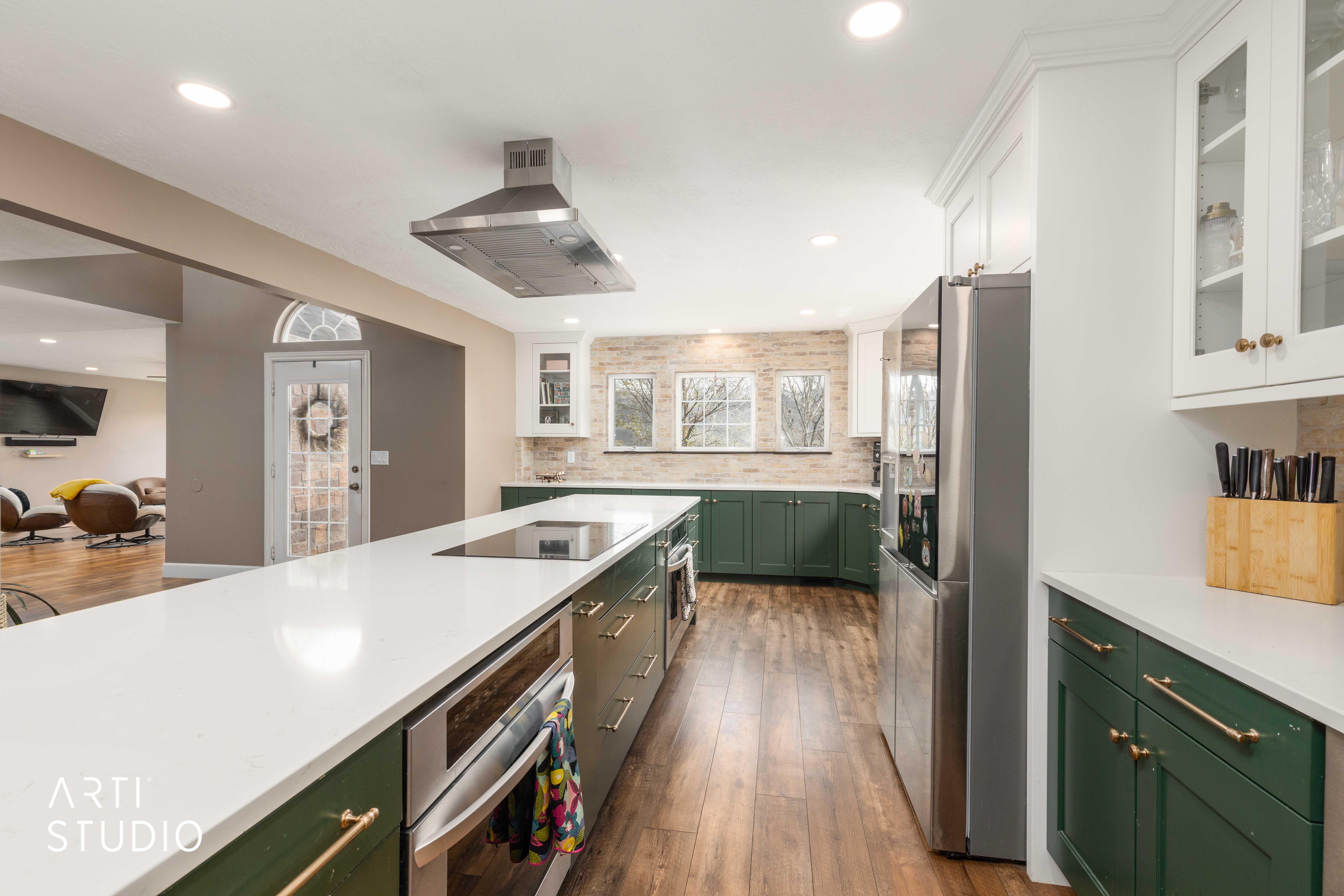 Kitchen with glass insert cabinets, dual tone cabinets, stainless steel appliances, island exhaust hood, and light stone countertops