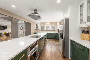 Kitchen with glass insert cabinets, dual tone cabinets, stainless steel appliances, island exhaust hood, and light stone countertops