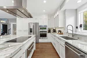Kitchen featuring marble countertops, an induction range and an island range hood, stainless steel Kitchen Aid appliances, and recessed lighting
