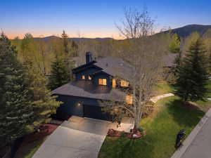 View of front of house featuring a mountain view, a lawn, driveway, an attached garage, and a shingled roof