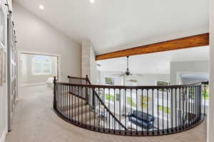 Hall featuring vaulted ceiling, light colored carpet, and an upstairs landing