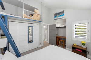 Bedroom with light colored carpet, vaulted ceiling, and a closet