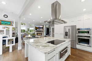 Kitchen featuring marble countertops, an induction range and an island range hood, stainless steel Kitchen Aid appliances, and recessed lighting