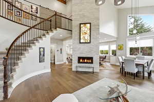 Living area with wood flooring, a fireplace, a high ceiling, and recessed lighting
