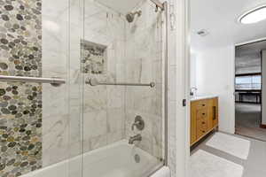 Bathroom with shower / bath combination with glass door, vanity, and light tile patterned flooring