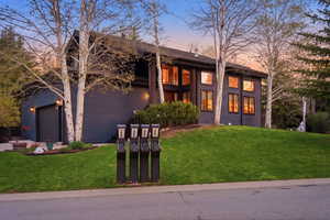 View of front of house featuring a mountain view, a lawn, driveway, an attached garage, and a shingled roof