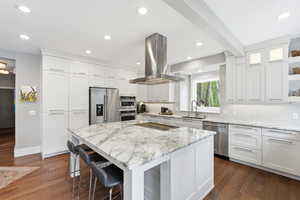 Kitchen featuring decorative backsplash, island exhaust hood, stainless steel appliances, marblecountertops, and recessed lighting