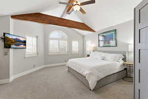 Primary Bedroom with beamed ceiling, plantation shutters, light colored carpet, and a ceiling fan