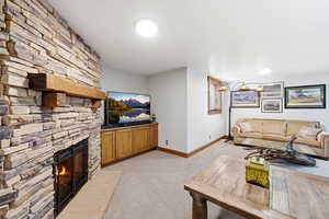 Living area featuring light carpet and a stone fireplace