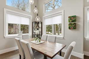 Dining area featuring a textured wall, wood finished floors, and a high ceiling