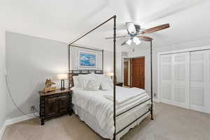 Bedroom with light carpet, ceiling fan, and a closet
