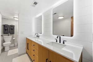 Full bathroom featuring double vanity, wooden walls, and light tile patterned flooring