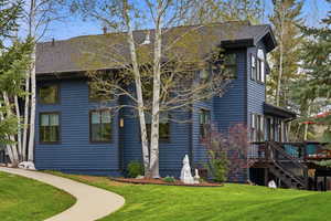 Rear view of property featuring a yard, a shingled roof, and a wooden deck