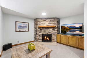 Living area with light colored carpet and a stone fireplace