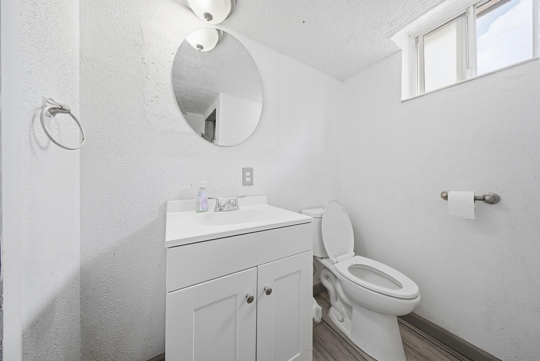 Bathroom with vanity, a textured wall, a textured ceiling, and wood finished floors