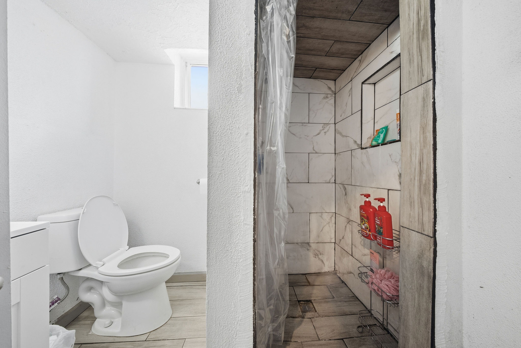 Bathroom featuring a shower stall, vanity, wood tiled floors, and a textured wall
