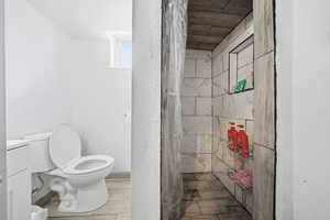Bathroom featuring a shower stall, vanity, wood tiled floors, and a textured wall