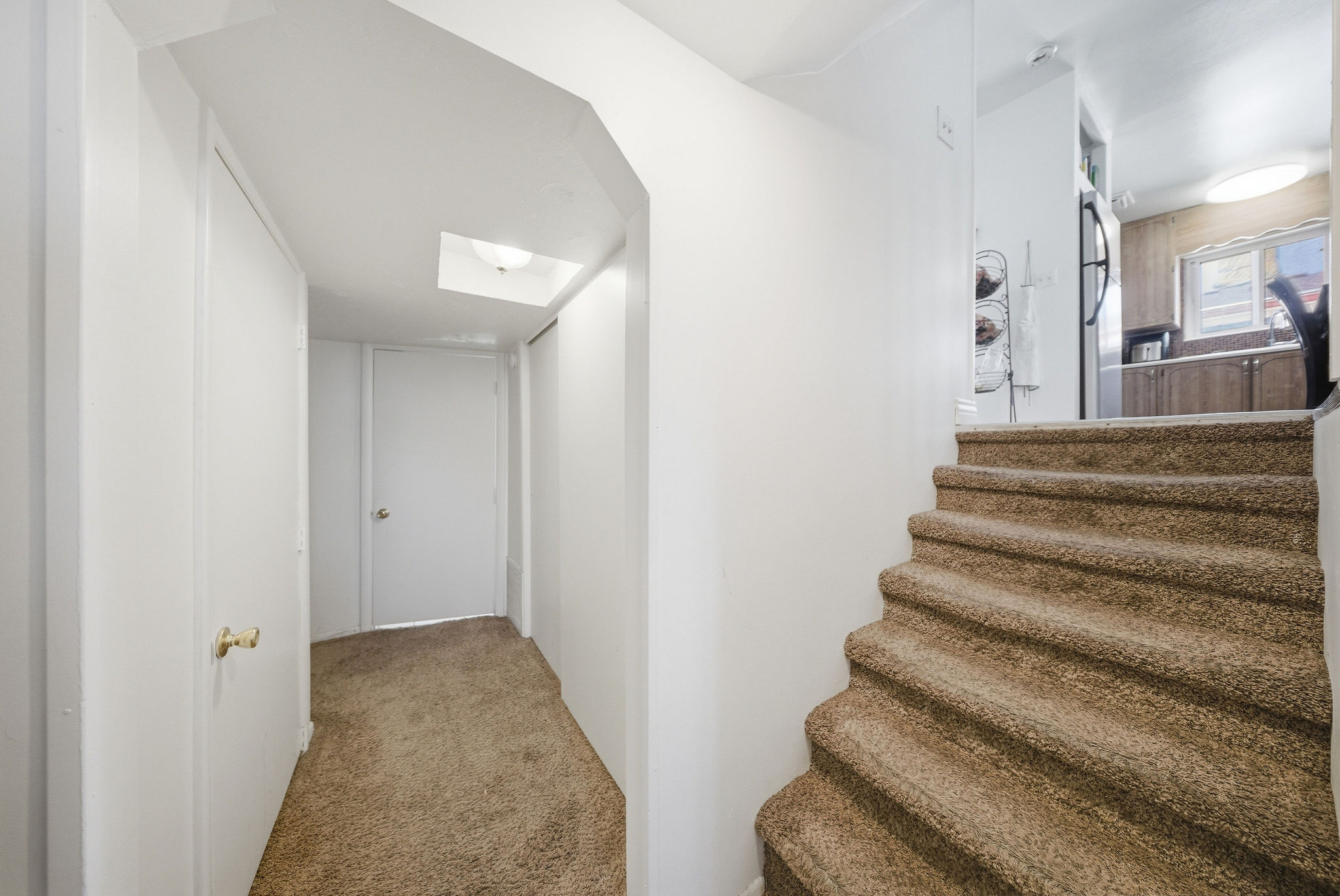 Carpeted staircase leading to an upper level with a partial view of a kitchen