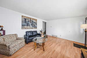 Living area with light wood-style floors and a textured ceiling