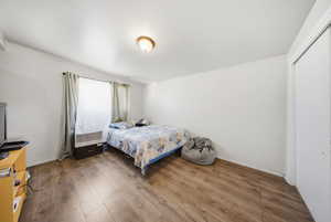 Bedroom featuring wood-finish flooring, white walls, and a recessed window