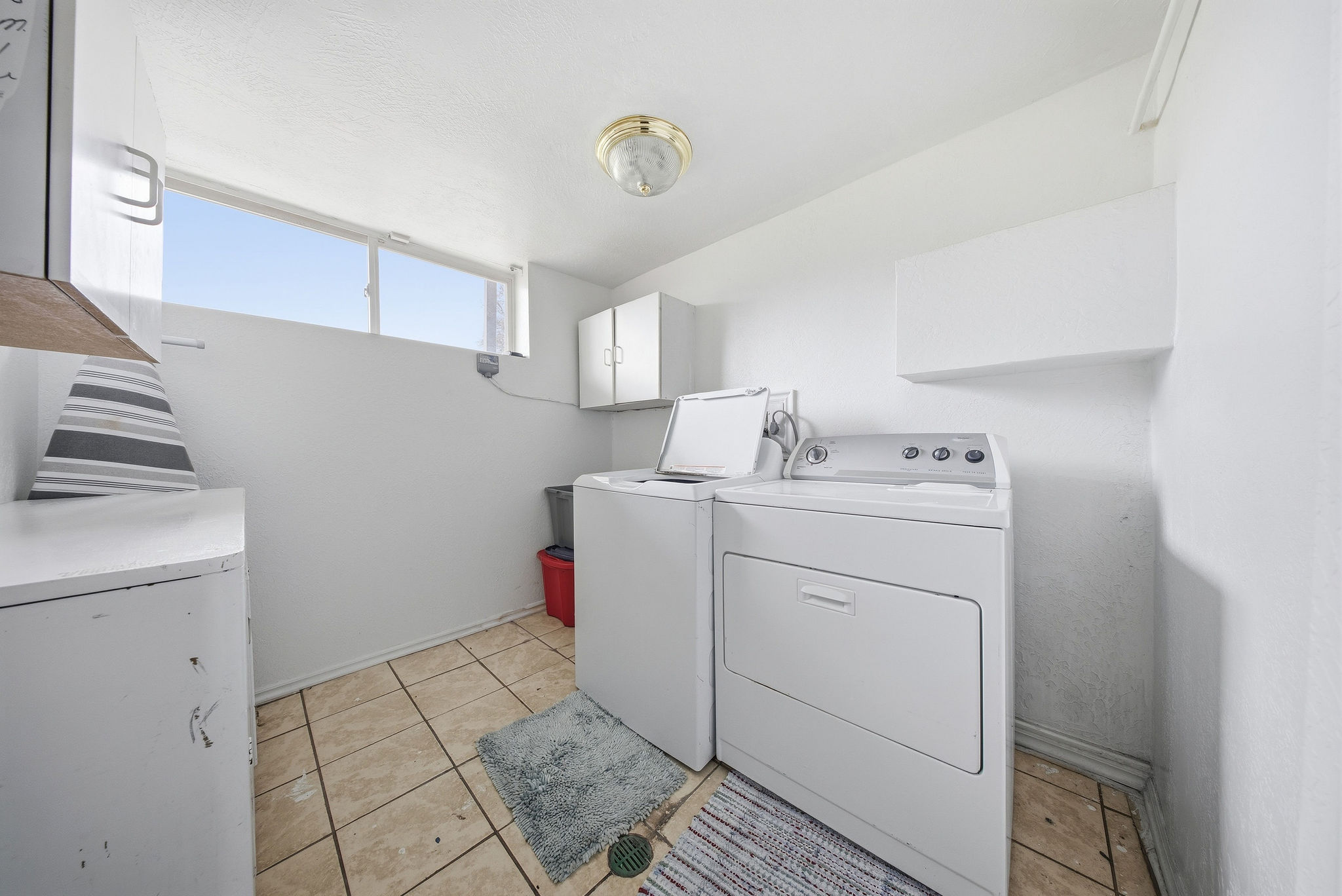 Laundry room featuring independent washer and dryer, light tile patterned floors, and cabinet space