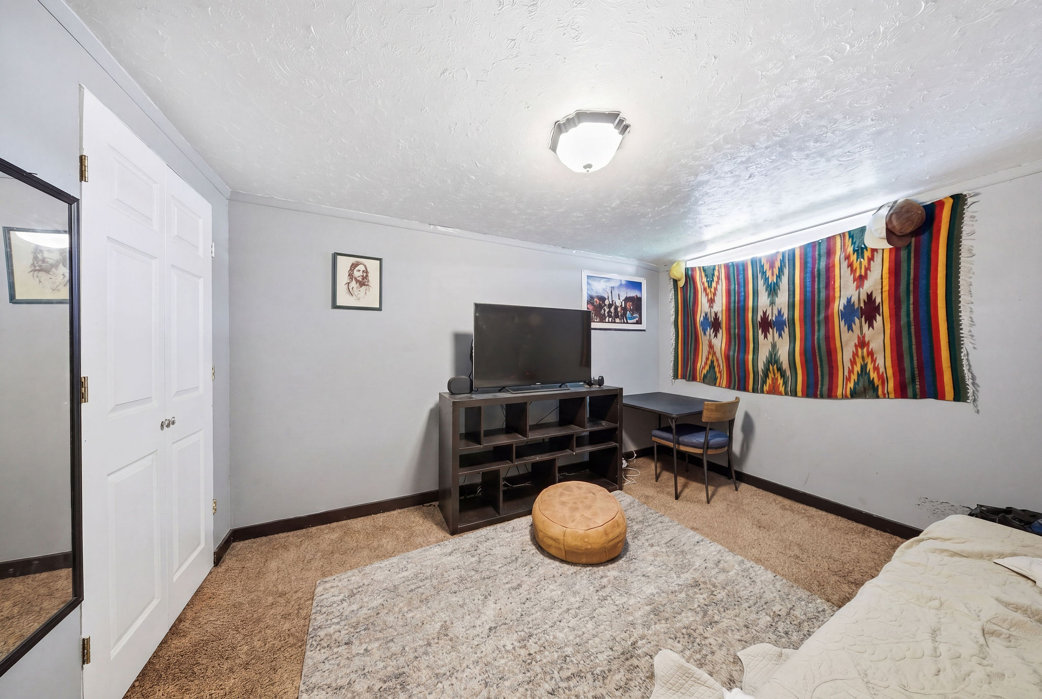 Carpeted interior space featuring light gray walls, white trim, and a white six-panel bi-fold closet door