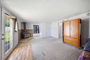 Carpeted interior space featuring a wood-burning stove with a brick surround and a corner hearth