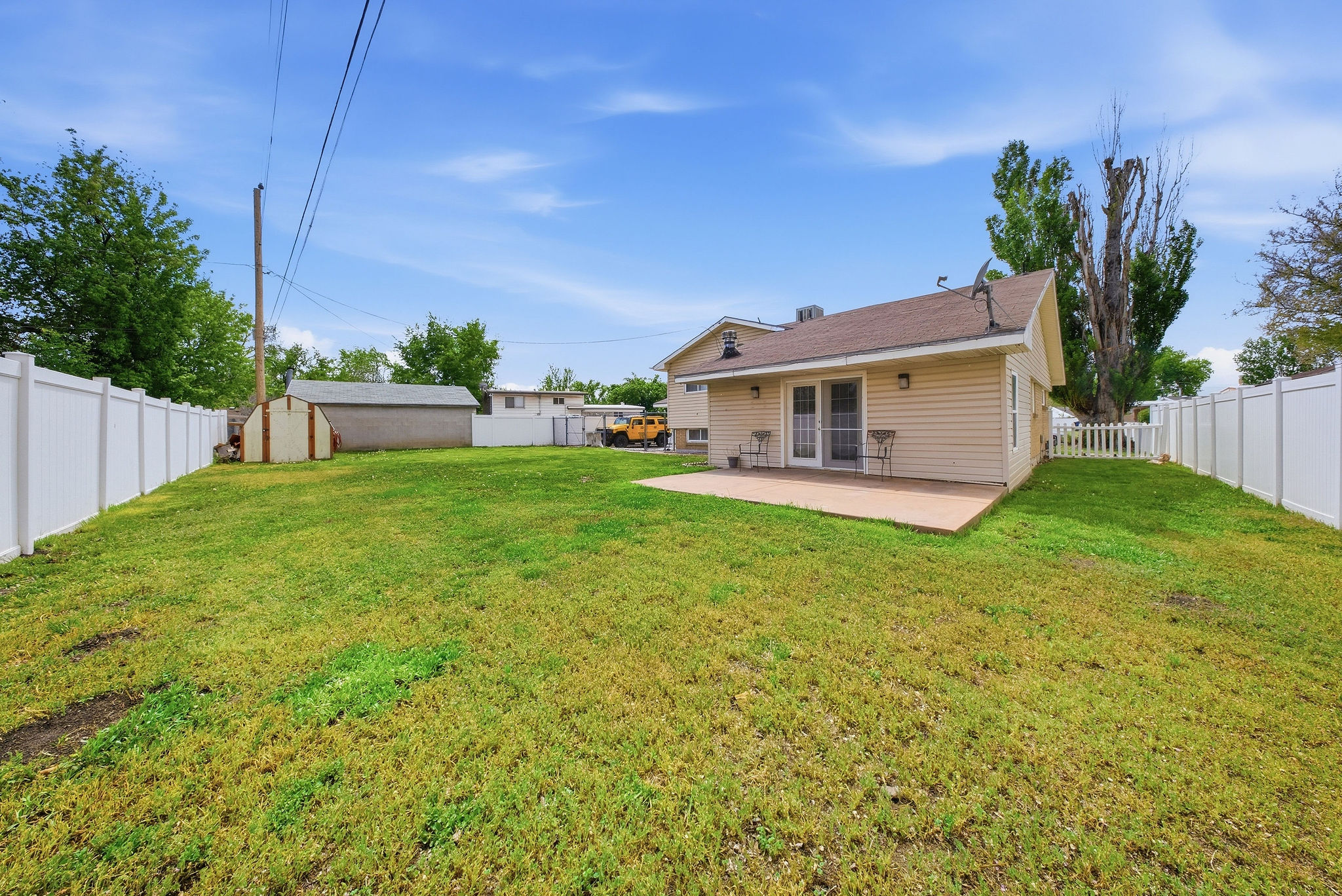 Back of house with a fenced backyard, a storage shed, and a patio