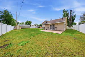 Back of house with a fenced backyard, a storage shed, and a patio