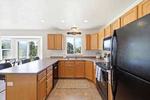 Kitchen featuring a peninsula, black appliances, a kitchen breakfast bar, recessed lighting, and a textured ceiling