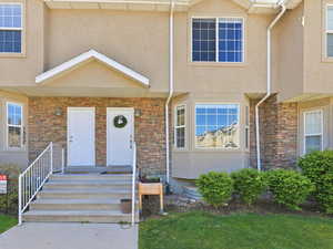 Doorway to property featuring stone siding and stucco siding