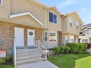View of front of home featuring stucco siding, stone siding, and a front lawn