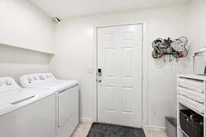 Laundry area with independent washer and dryer and light tile patterned floors