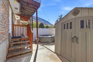 Fenced backyard with a patio, a mountain view, and a storage unit